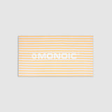 Toalla Monoic blanca con líneas amarillas gruesas y la palabra Monoic escrita horizontalmente.